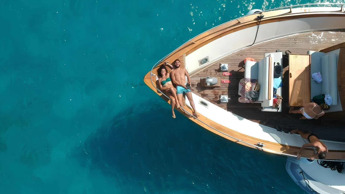 White tour boat anchored in a turquoise bay off the coast of Ischia on an Ischia island boat tour with lunch, Campania, Italy